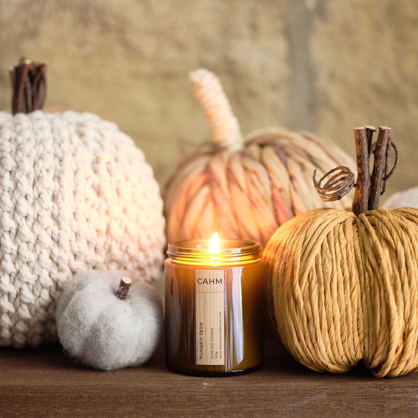 Candle with decorative pumpkins on a wooden surface
